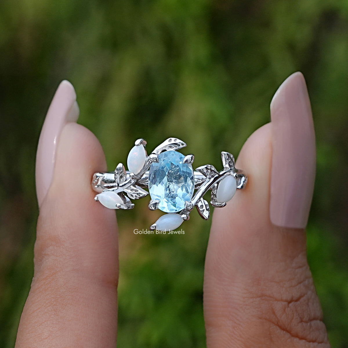 Two fingers holding the Aquamarine Oval Gemstone Leaf Style Ring