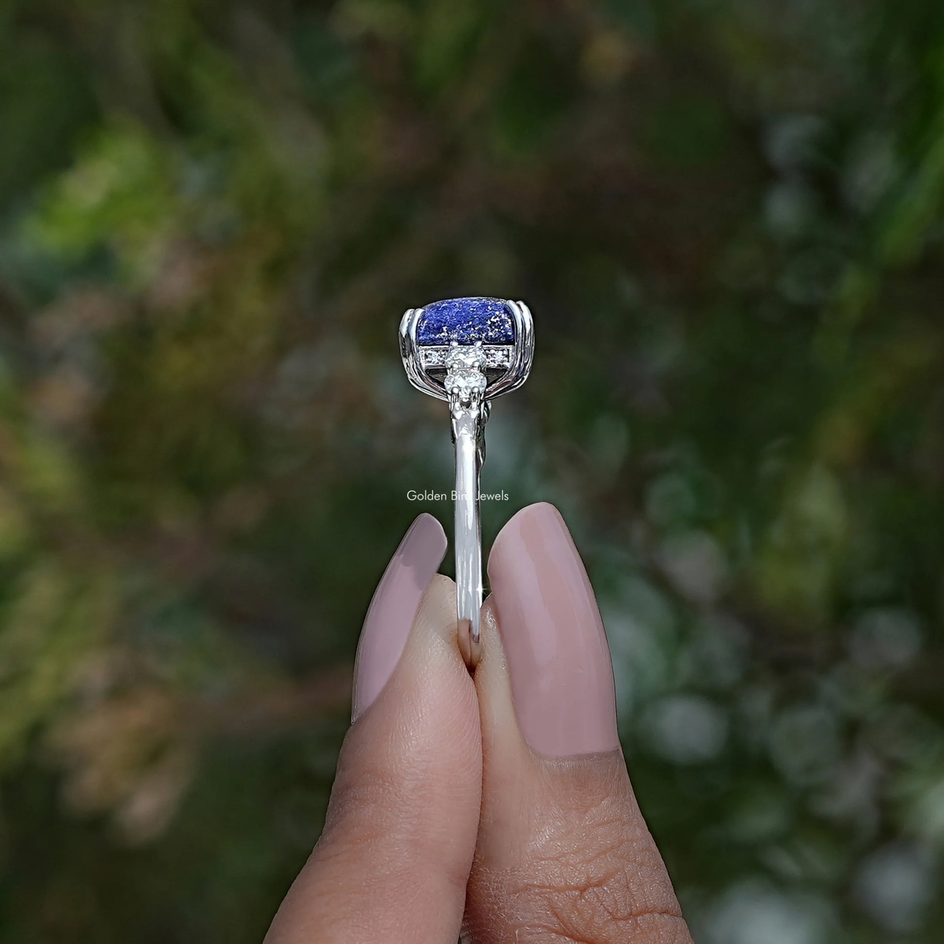 Side View of Emerald Cut Hidden Halo Accent Stone Ring In two fingers
