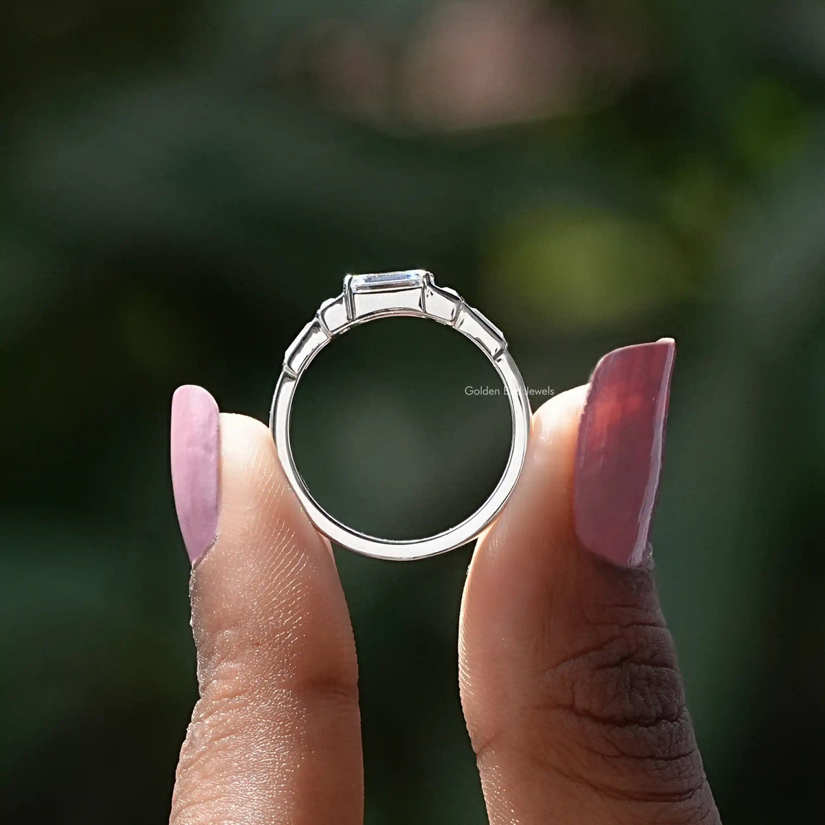 Back View of Emerald And Baguette Moissanite Ring In two fingers