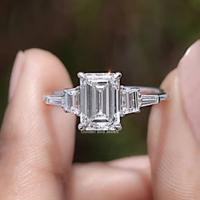 Emerald And Tapered Baguette Lab Diamond Ring Between Two Fingers