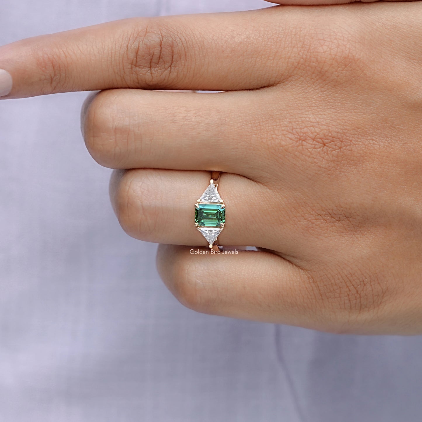 View of solitaire Emerald And Triangle Moissanite Three Stone Ring in prongs setting 