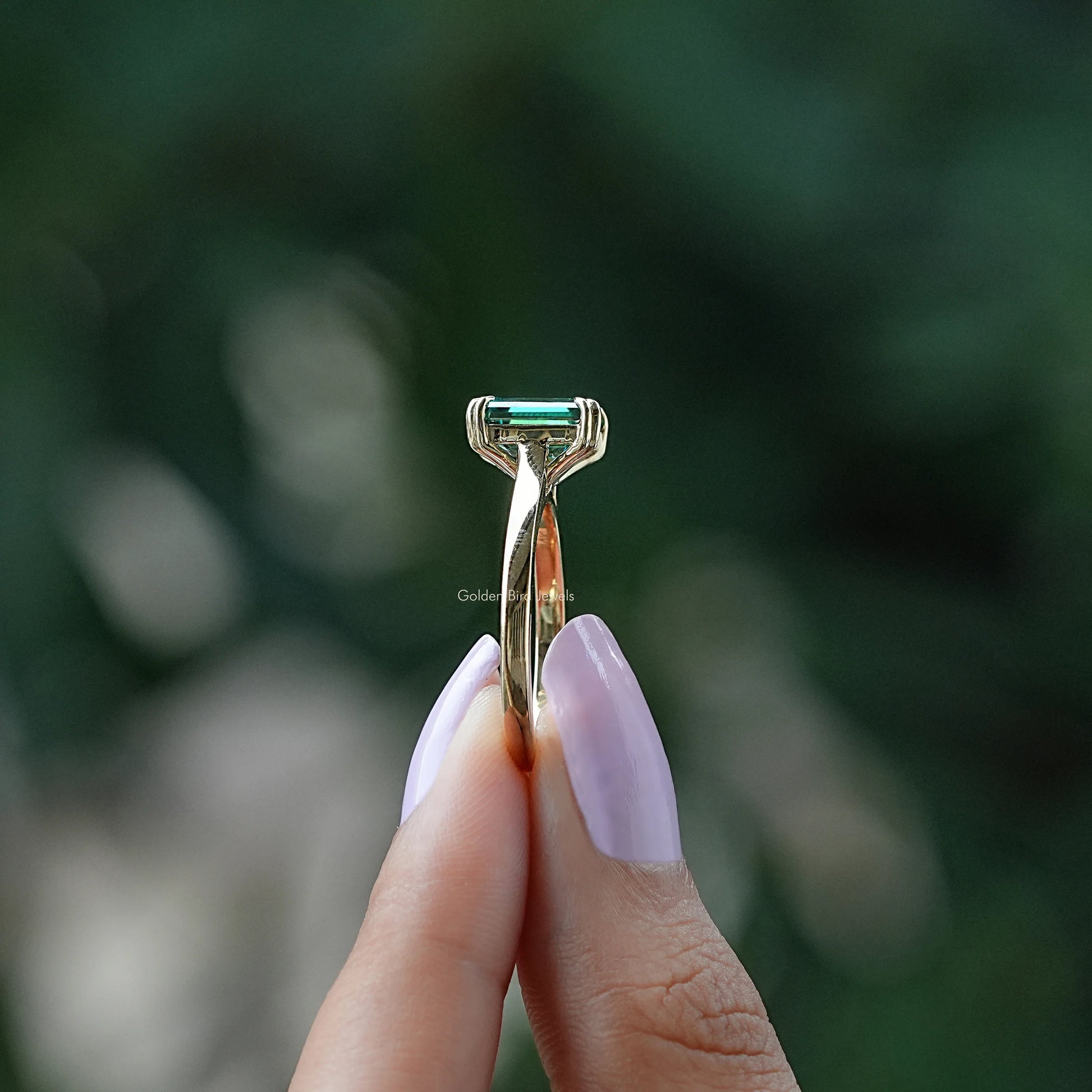 Side view of moissanite ring holding on two fingers 