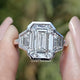 Front view of Bezel Set Emerald Cut Lab Diamond Three Stone Ring in two fingers 