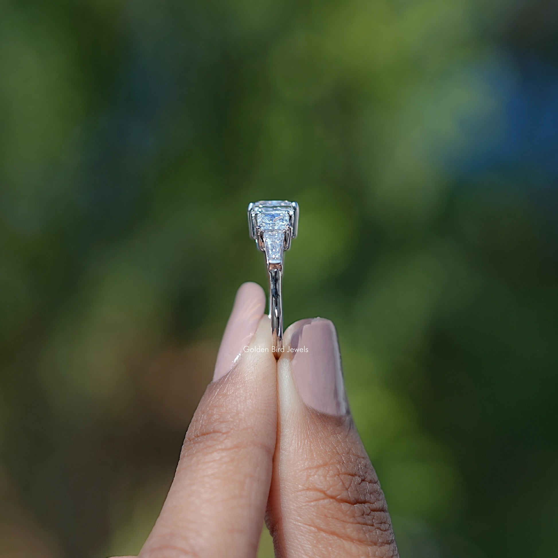 Side View of Princess Cut Diamond Five Stone Engagement Ring In two fingers