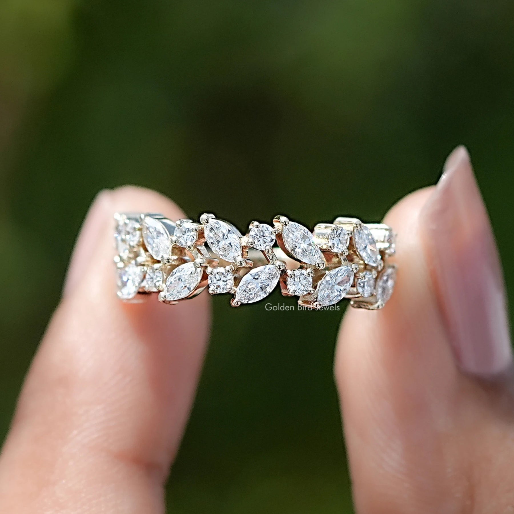 Marquise and Round Cut Lab Diamond Wedding Band Held Between Fingers