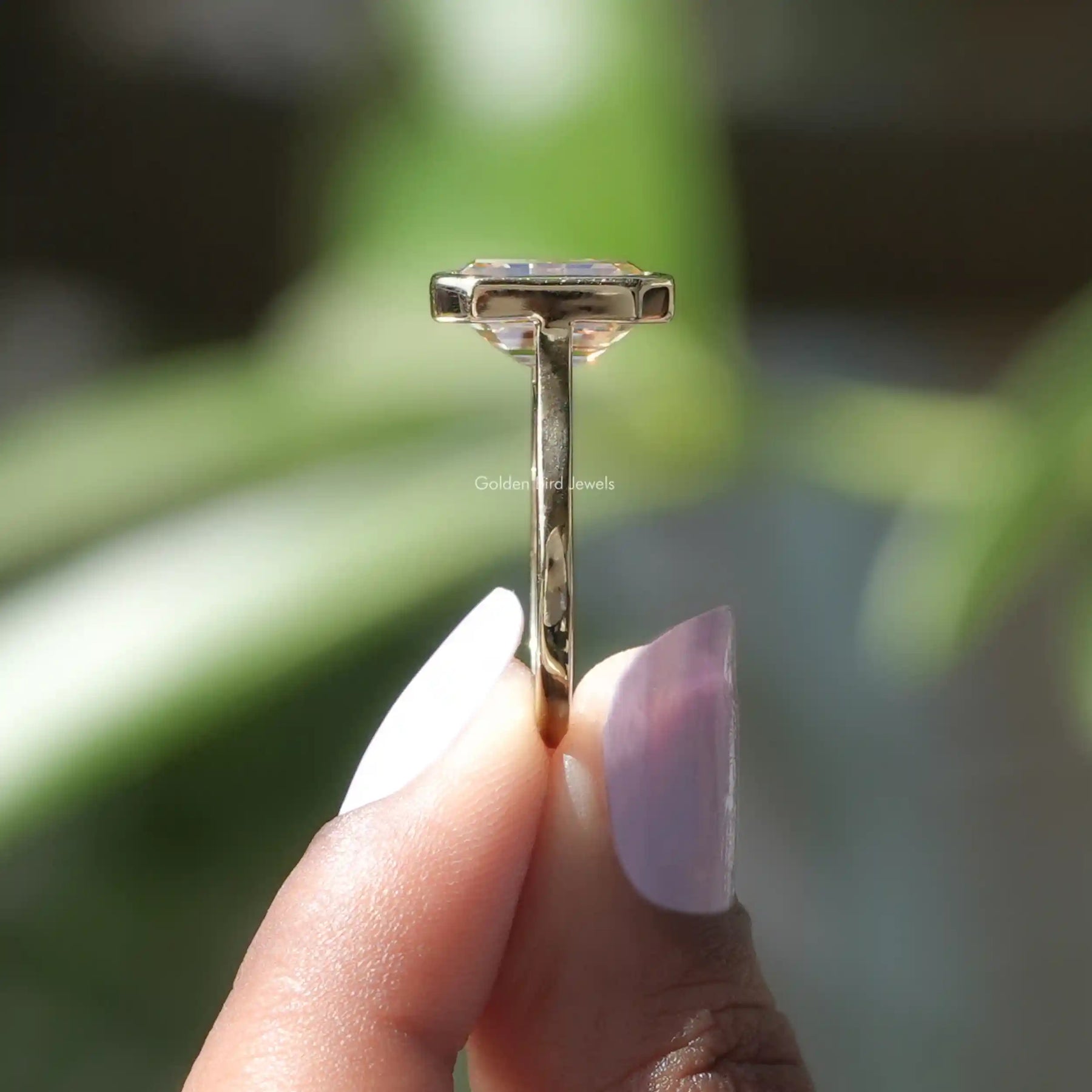 Side View of Emerald Cut Solitaire Engagement Ring In two fingers