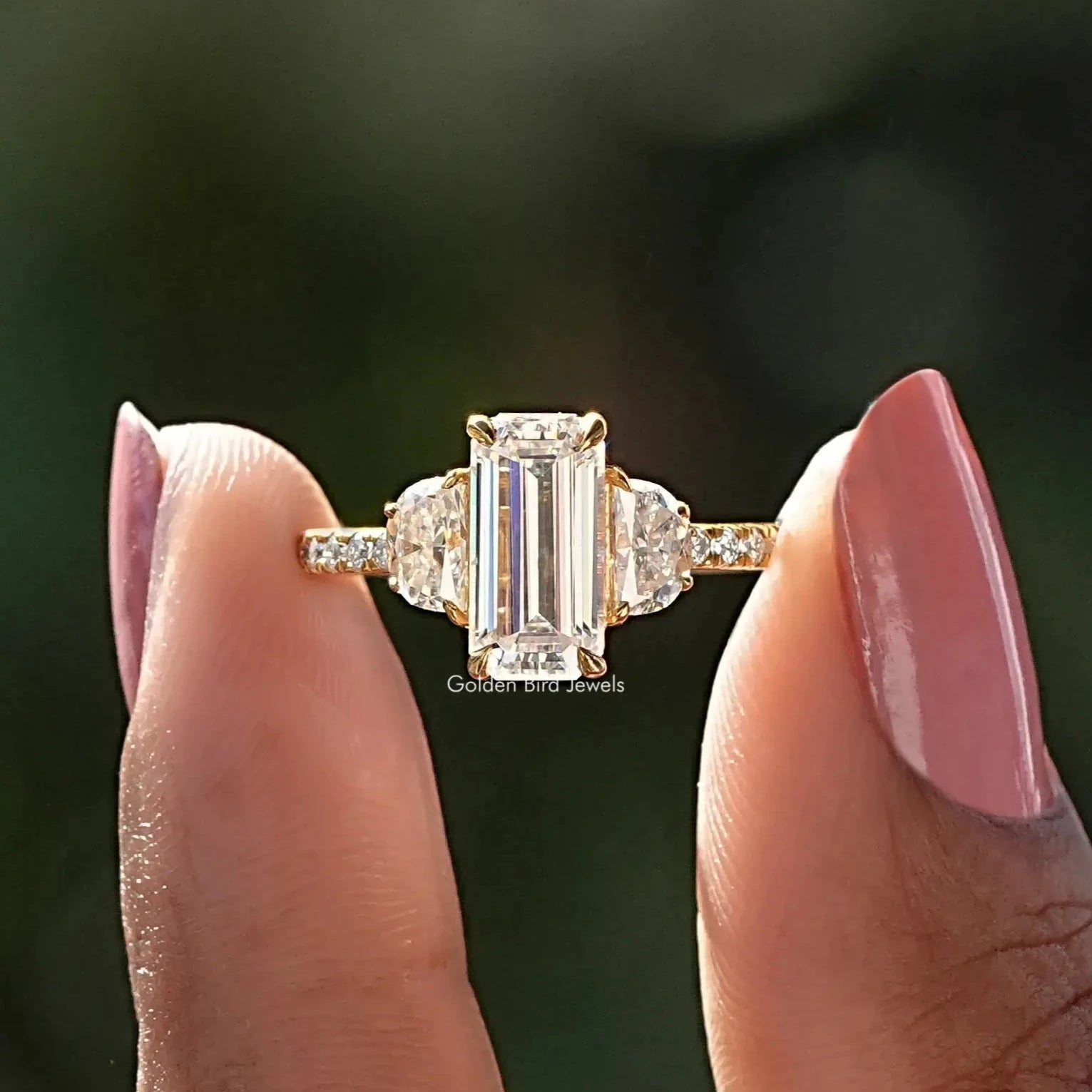 Two fingers holding the Emerald Cut Three Stone Engagement Ring