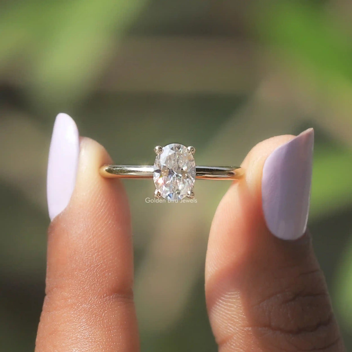 Two fingers holding the Oval Cut Hidden Halo Moissanite Ring 