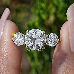 Old European Round Diamond Three Stone Ring Held Between Fingers