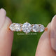 Heart And Round Cut Lab Diamond Five Stone Ring Held Between Fingers