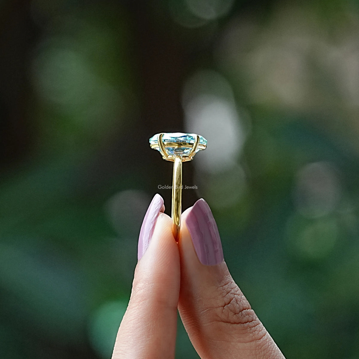 Side View of Yellow Gold Moval Cut Moissanite Ring In two fingers