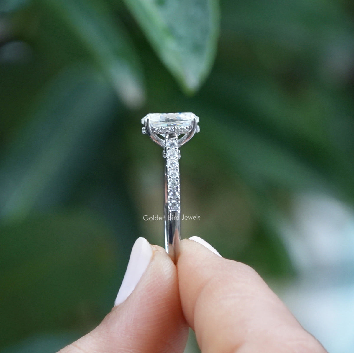 Side View Of Oval Cut Hidden Halo Engagement Ring In A two Fingers