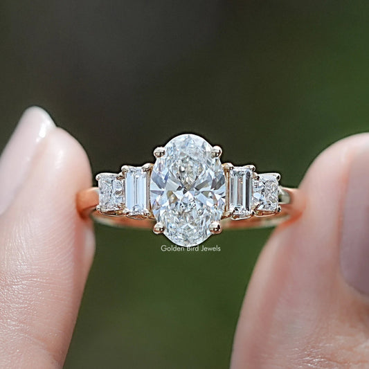 Oval Cut Lab Diamond Five Stone Engagement Ring BetweenTwo Fingers