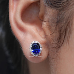 Close-up of an ear wearing a blue gemstone earring with a blurred background