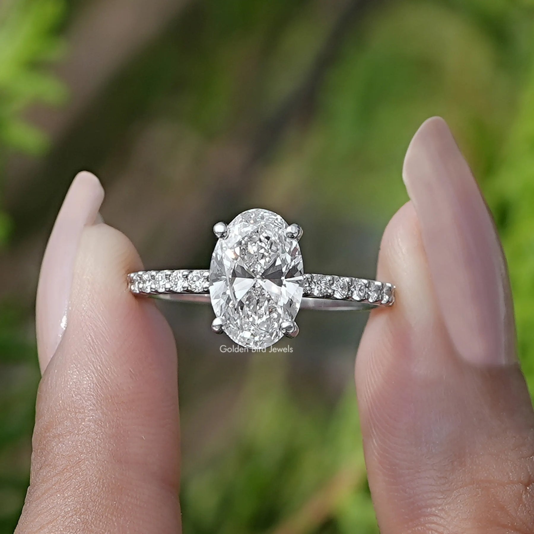 Two fingers holding the Oval Cut Diamond Engagement Ring