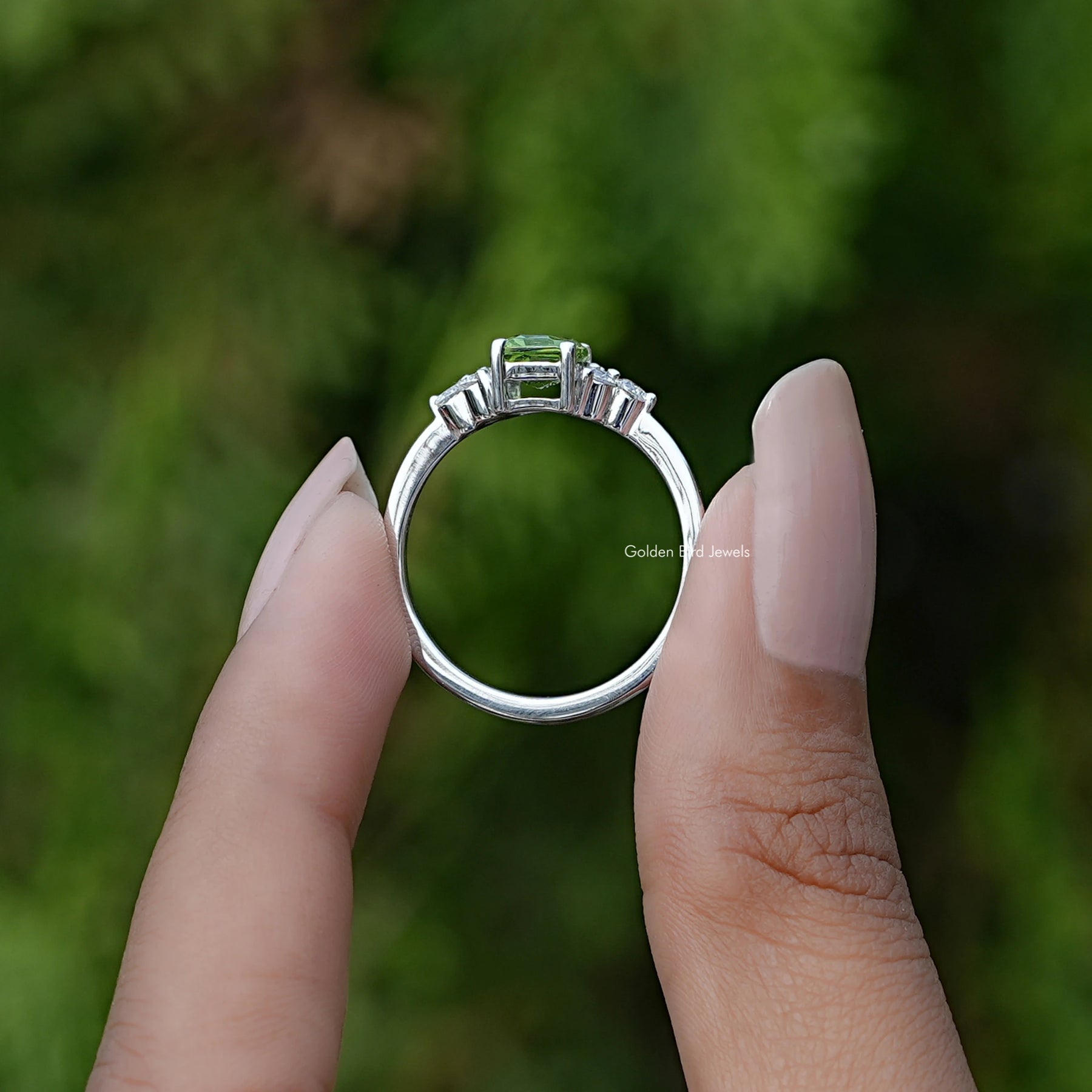 Back View of Green Emerald Cut Gemstone Engagement Ring In two fingers