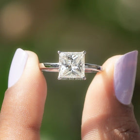 Two fingers holding the Princess Cut Moissanite Solitaire Ring