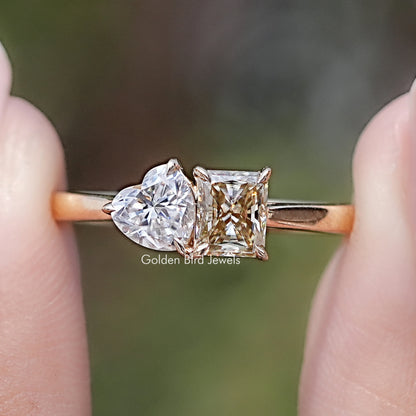 Front view of Radiant And Heart Cut Moissanite Two Stone Ring in two fingers 
