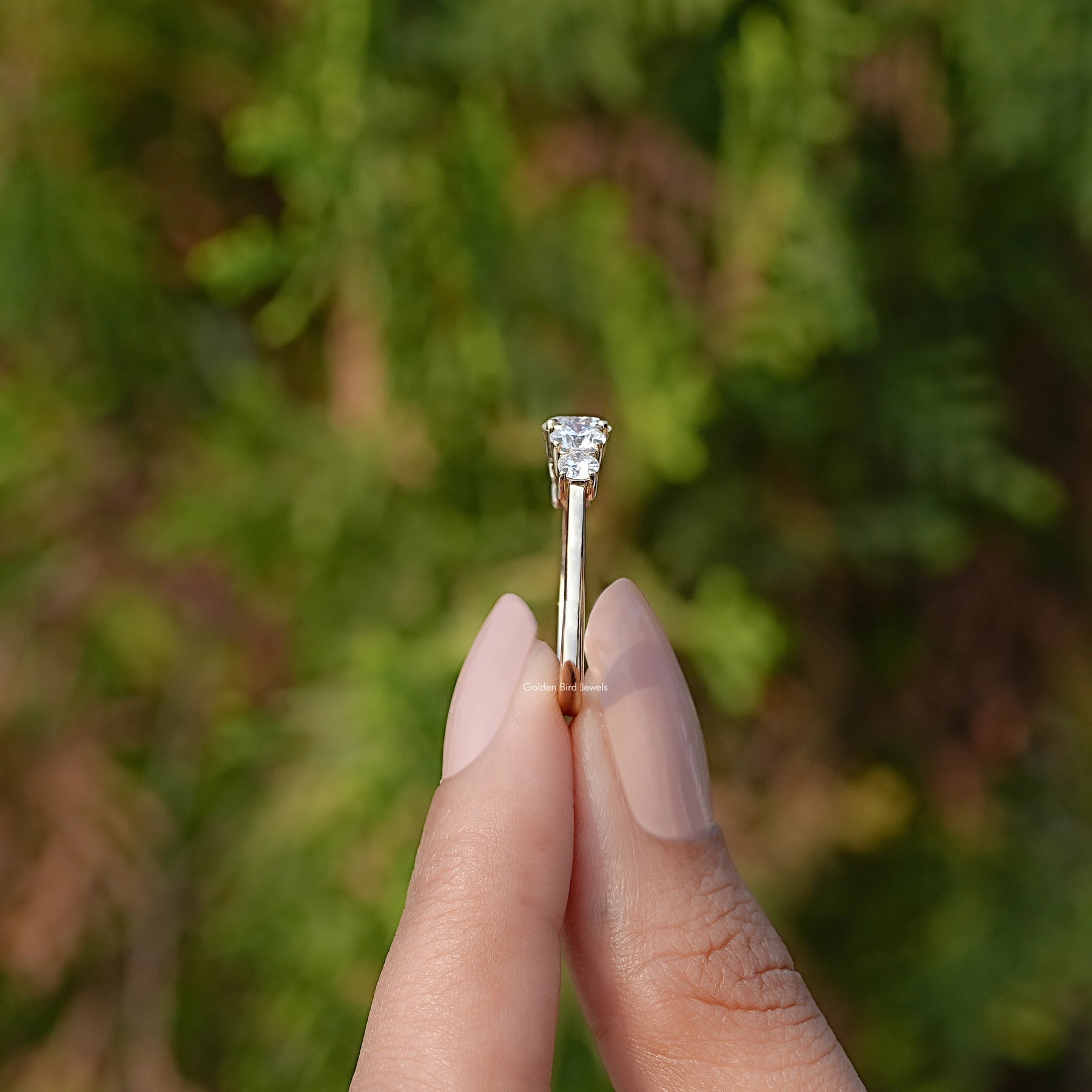 Side View of Round Cut Diamond Five Stone Accent Ring In two fingers