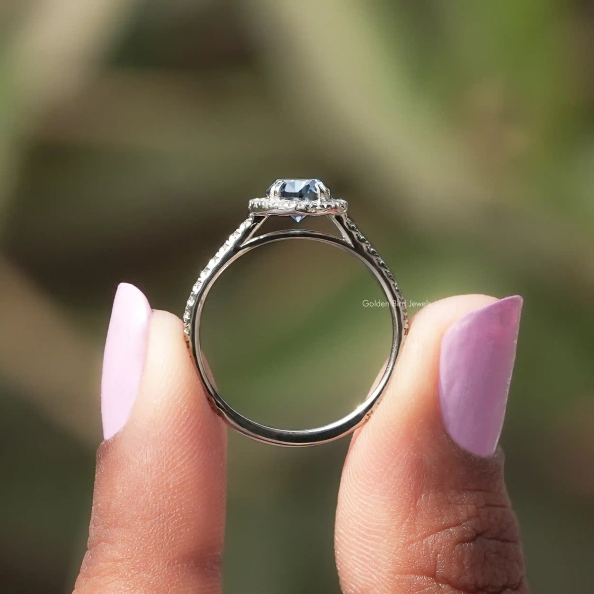 Back View of Sapphire Blue Oval Cut Halo Wedding Ring In two fingers