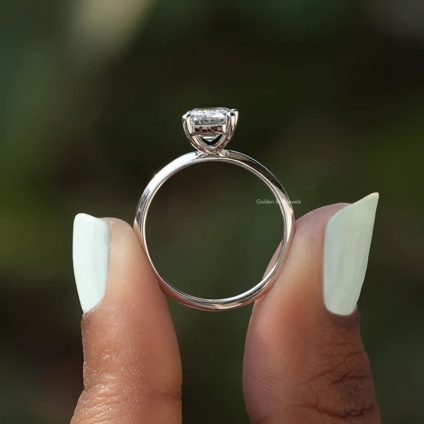 Back View of Emerald Cut Diamond Engagement Ring In two fingers