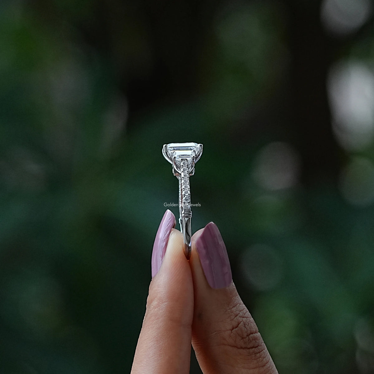 Side View of Emerald Cut Moissanite Engagement Ring In two fingers